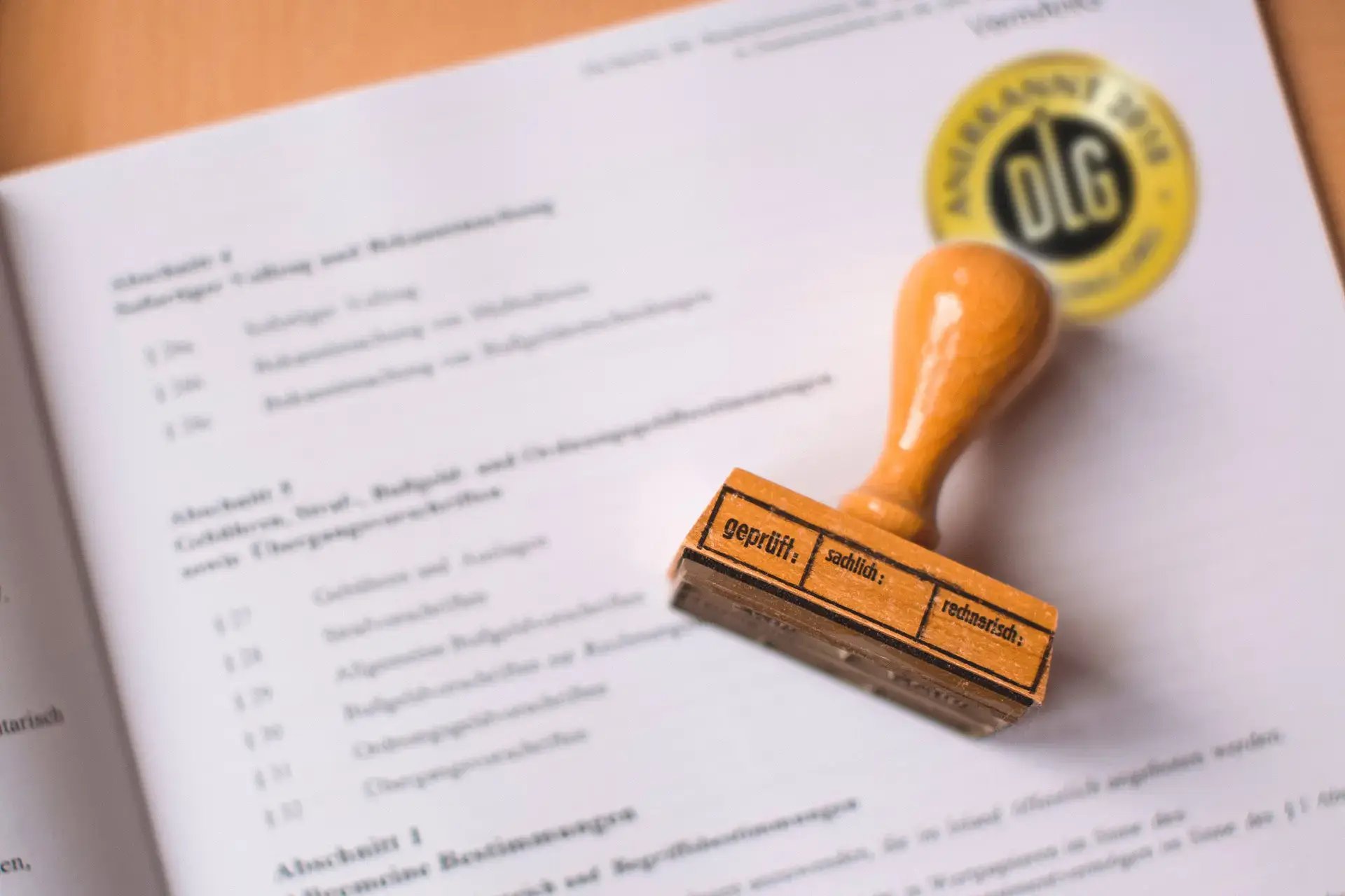 Ein Holzstempel liegt auf einem Garantiedokument mit goldenem Prüfsiegel.